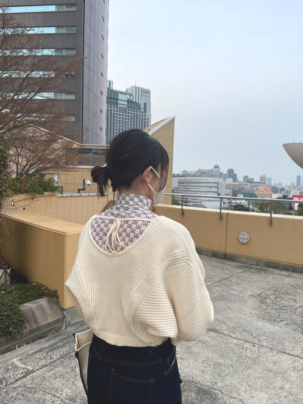 ホワイト系のトップス、ベージュ系のカーディガン/ボレロ、ブルー系のデニムスカートを着用したレディースの春コーディネートの3枚目の写真
