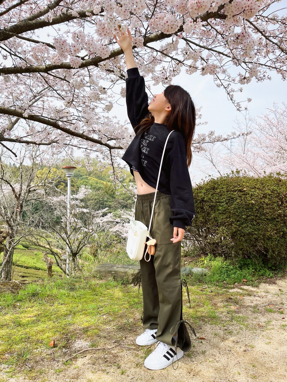 ブラック系のトップス、グリーン系のカーゴパンツ、ホワイト系のショルダーバッグを着用したキッズの春コーディネートの2枚目の写真