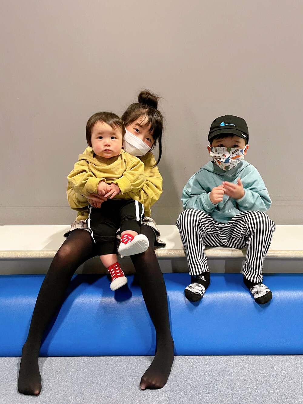 イエロー系のパーカー、ブルー系のパーカー、イエロー系のパーカーを着用したキッズの冬コーディネートの3枚目の写真