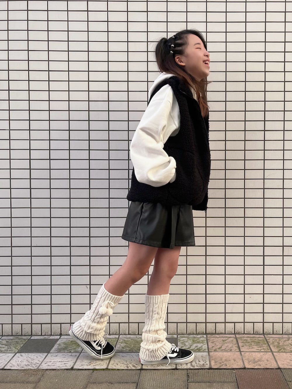 ブラック系のベスト、ホワイト系のパーカー、ブラック系のパンツを着用したキッズの秋コーディネートの2枚目の写真