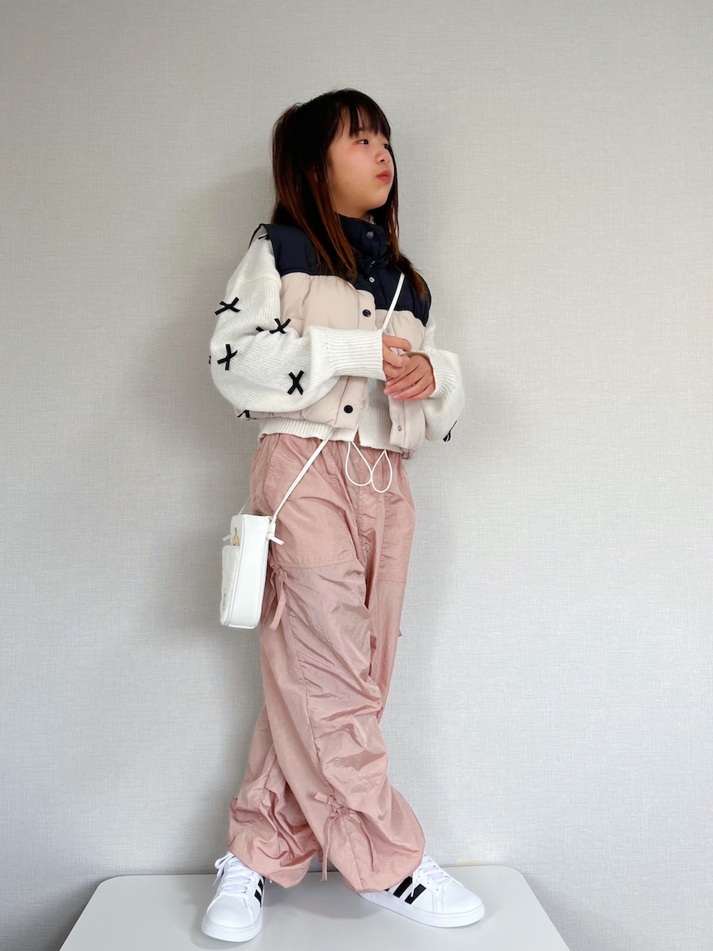 ホワイト系のベスト、ホワイト系のニット/セーター、ピンク系のカーゴパンツを着用したキッズの冬コーディネートの3枚目の写真