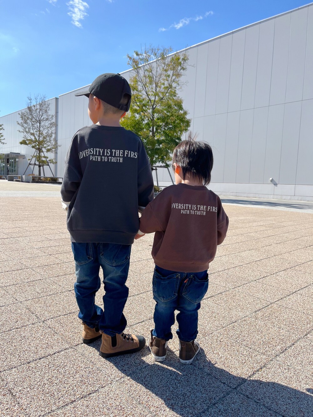 ブラック系のスウェット、ブルー系のデニムパンツ、ブラウン系のスウェットを着用したキッズの秋コーディネートの2枚目の写真