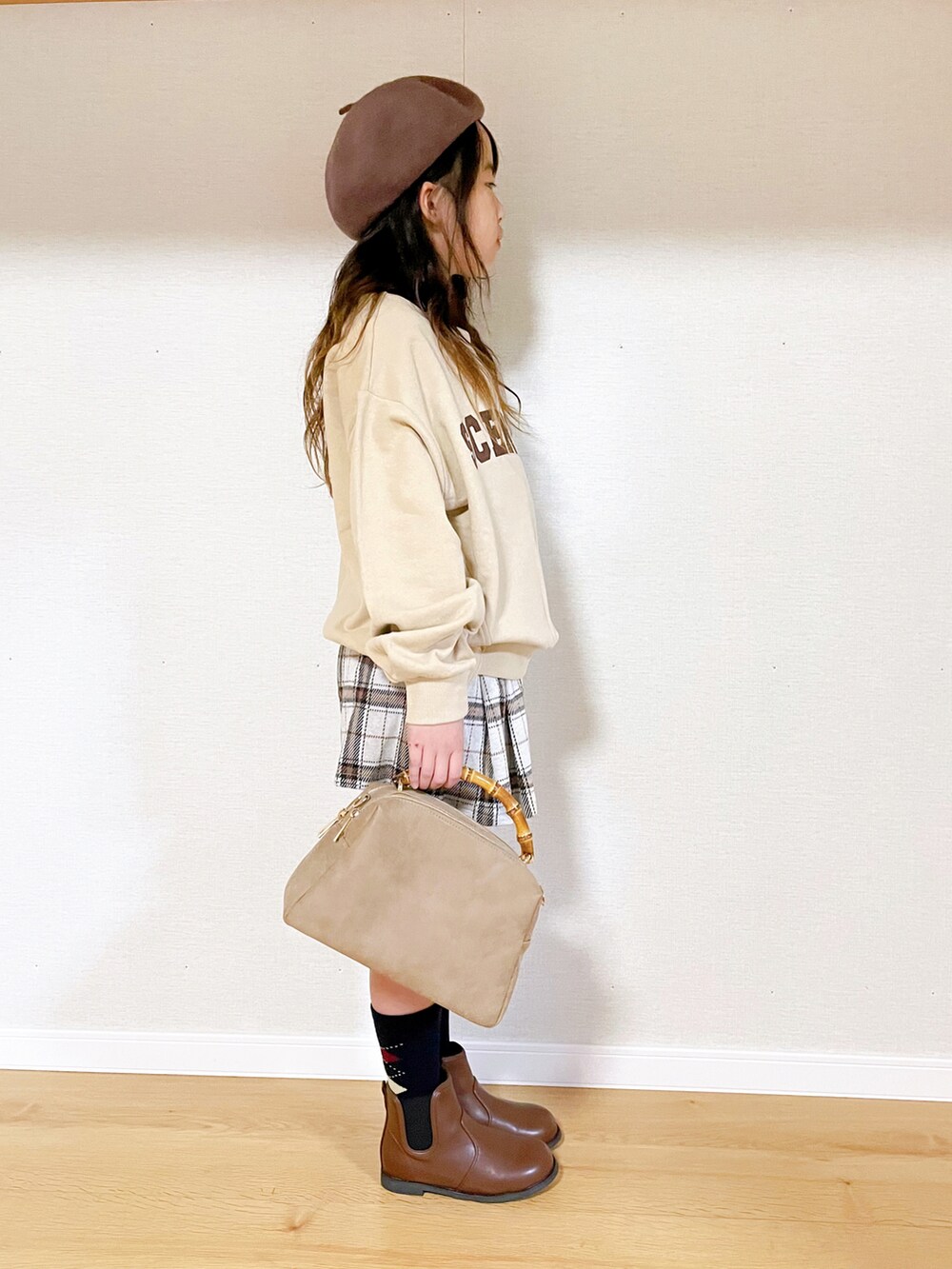 ベージュ系のスウェット、ホワイト系のスカート、ベージュ系のショルダーバッグを着用したキッズの冬コーディネートの2枚目の写真