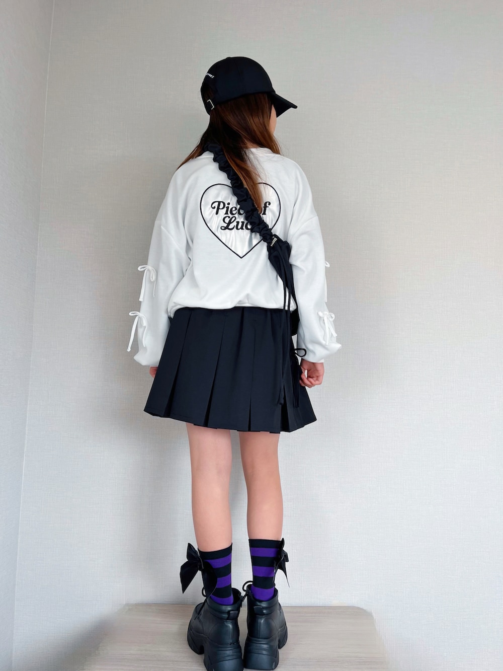 ブラック系のショルダーバッグ、ホワイト系のトップス、ブラック系のスカートを着用したキッズの冬コーディネートの2枚目の写真