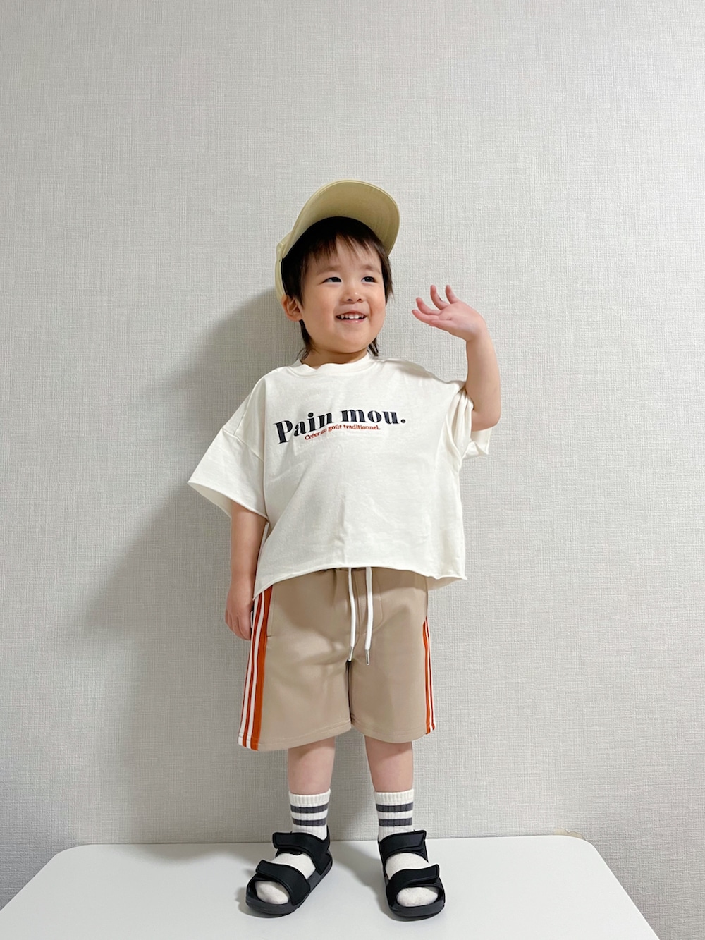 ホワイト系のTシャツ/カットソー、ベージュ系のパンツ、ブラウン系のキャップを着用したキッズの冬コーディネートの2枚目の写真