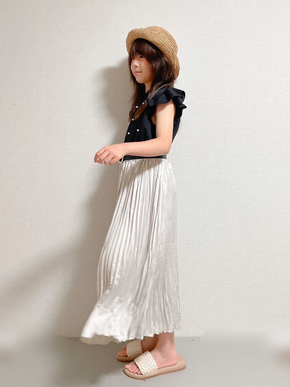 ブラック系のトップス、グレー系のスカート、ベージュ系のサンダルを着用したキッズの夏コーディネートの3枚目の写真