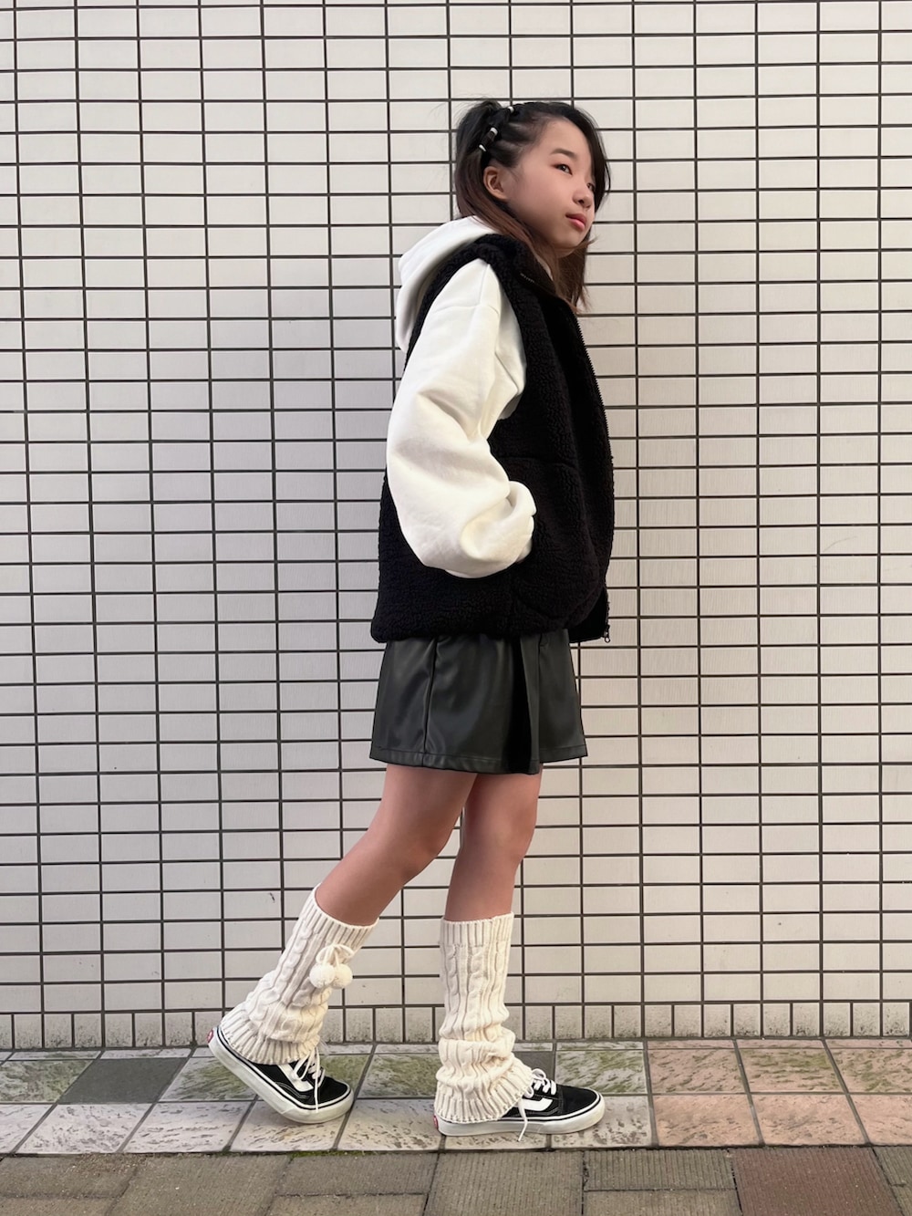 ブラック系のベスト、ホワイト系のパーカー、ブラック系のパンツを着用したキッズの秋コーディネートの3枚目の写真