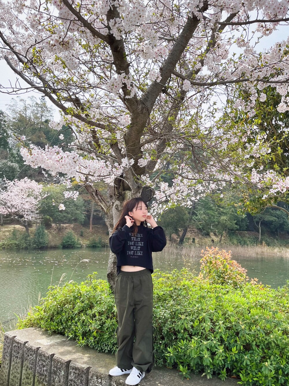 ブラック系のトップス、グリーン系のカーゴパンツ、ホワイト系のショルダーバッグを着用したキッズの春コーディネートの4枚目の写真