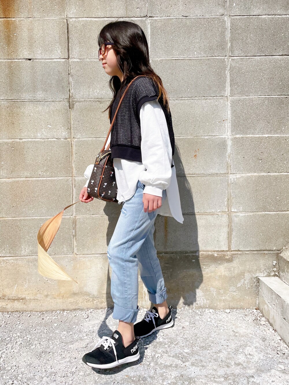 ブラック系のTシャツ/カットソー、ブルー系のその他パンツ、ブラウン系のボストンバッグを着用したキッズの春コーディネートの2枚目の写真