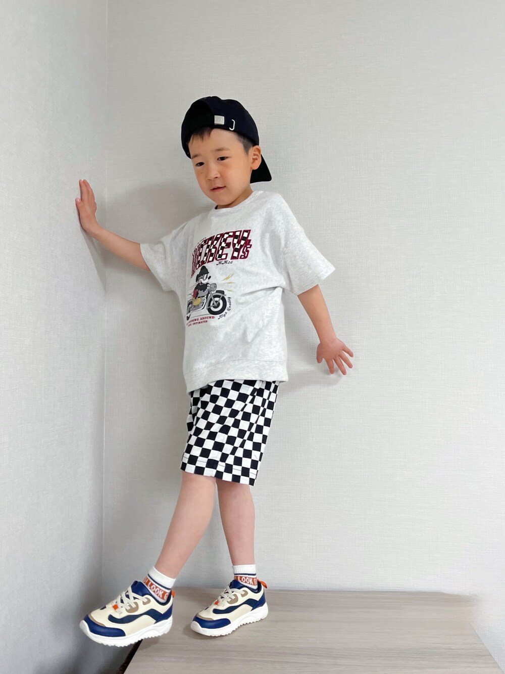 ブラック系のパンツ、ホワイト系のTシャツ/カットソー、ブルー系のスニーカーを着用したキッズの春コーディネートの2枚目の写真