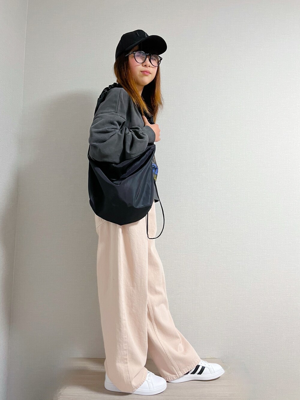 グレー系のトップス、ピンク系のデニムパンツ、ホワイト系のスニーカーを着用したキッズの冬コーディネートの2枚目の写真