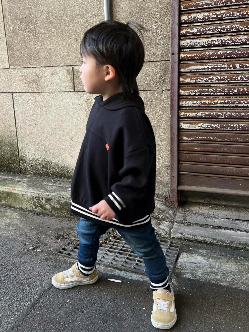 ブラック系のパーカー、ブルー系のデニムパンツ、ベージュ系のスニーカーを着用したキッズの冬コーディネートの2枚目の写真