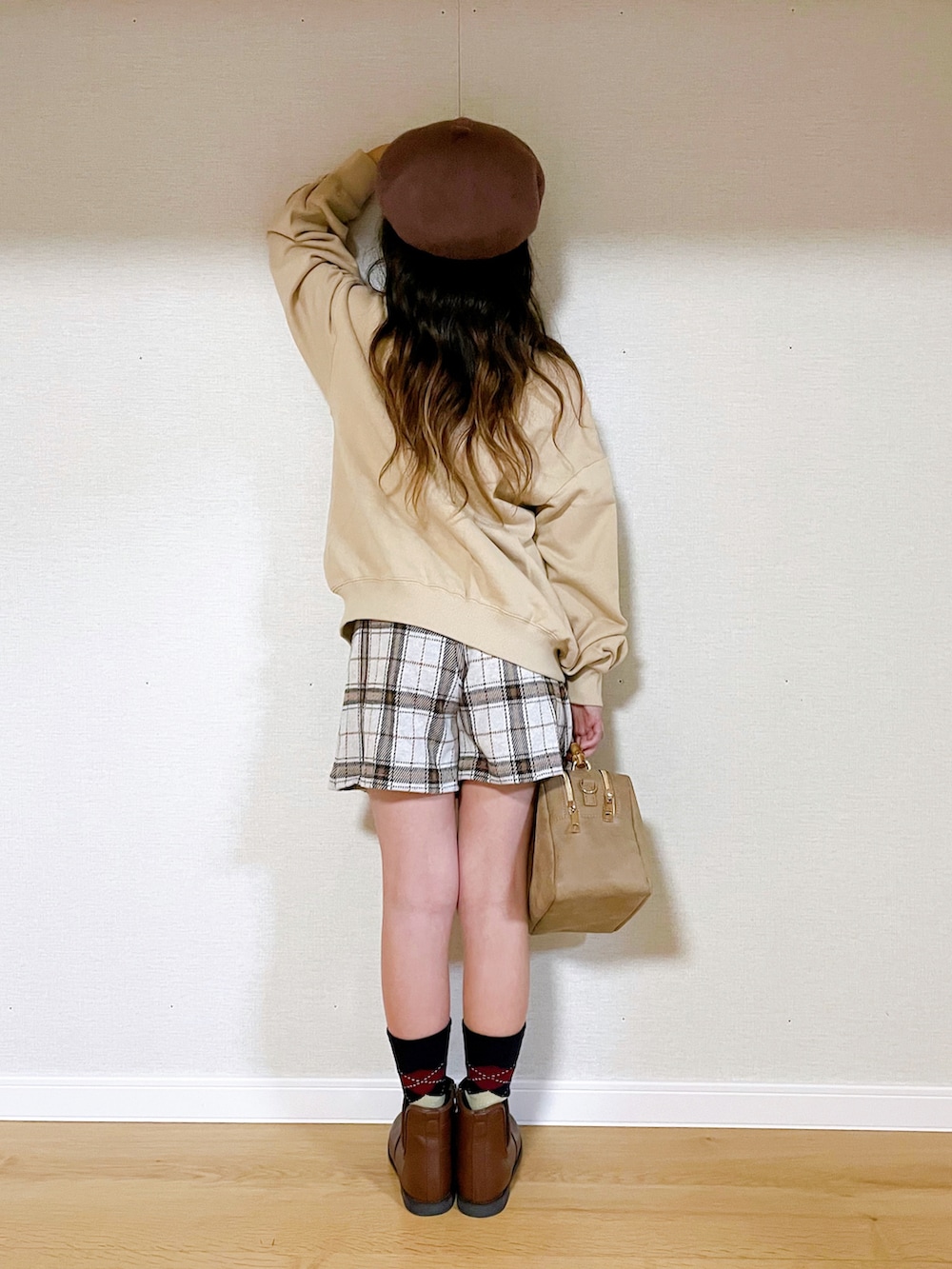 ベージュ系のスウェット、ホワイト系のスカート、ベージュ系のショルダーバッグを着用したキッズの冬コーディネートの3枚目の写真