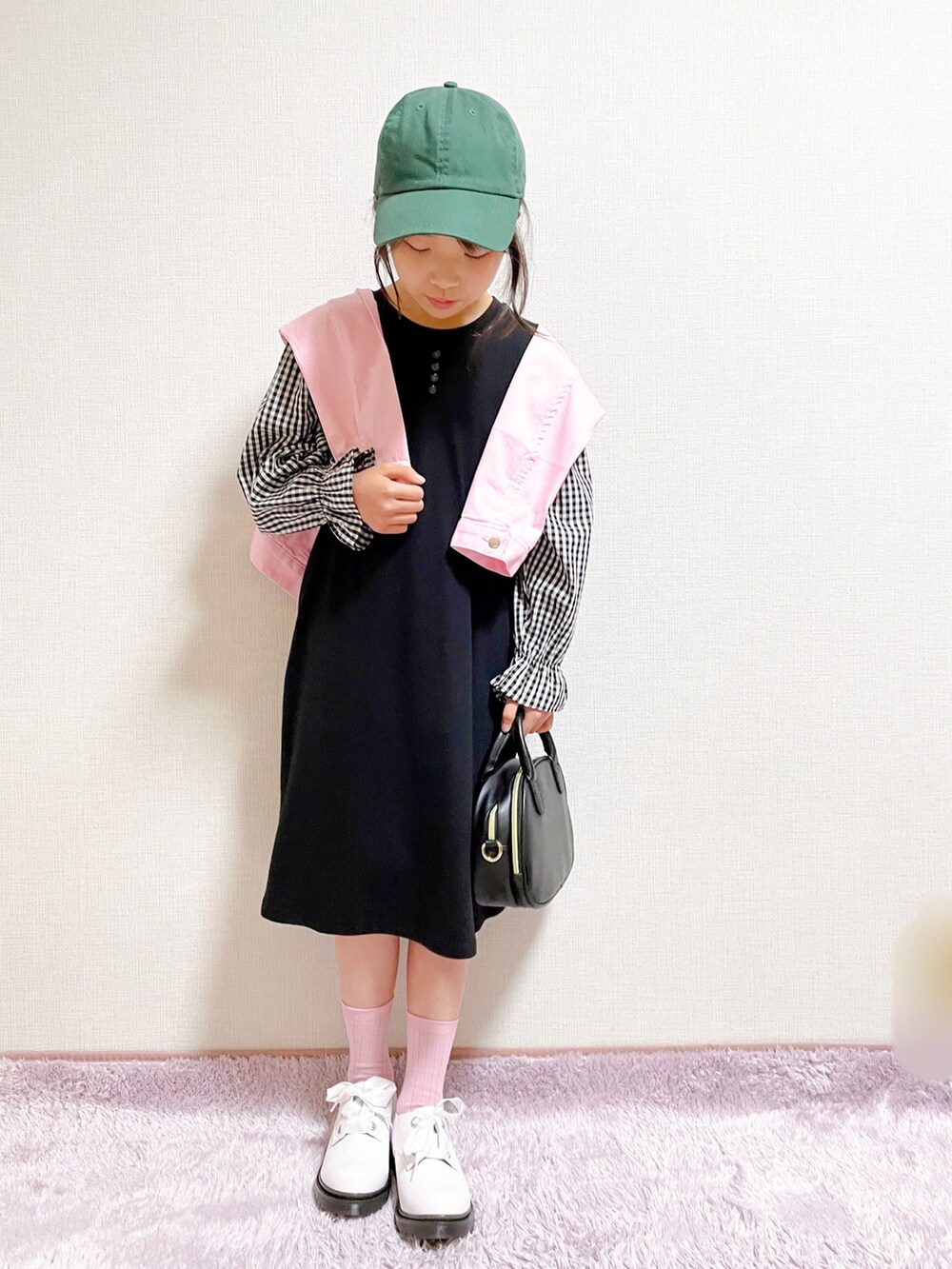 ブラック系のワンピース、ピンク系のジャケット/アウター、ブラック系のショルダーバッグを着用したキッズの春コーディネートの2枚目の写真