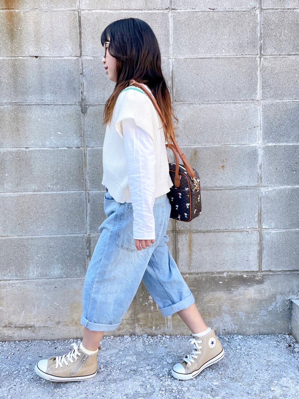 ホワイト系のベスト、ブルー系のデニムパンツ、ベージュ系のスニーカーを着用したキッズの春コーディネートの2枚目の写真