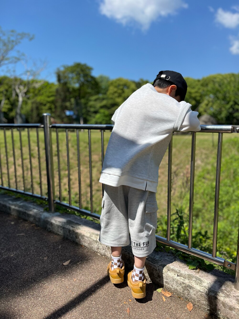 グレー系のトップス、グレー系のカーゴパンツ、ブラック系のキャップを着用したキッズの春コーディネートの3枚目の写真