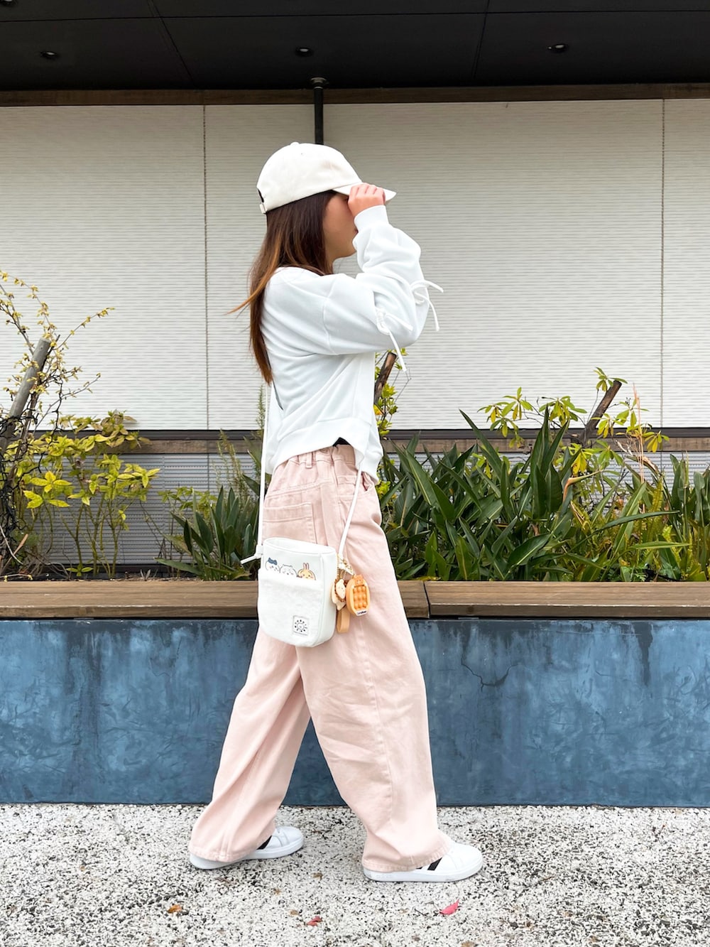 ホワイト系のトップス、ピンク系のデニムパンツ、ホワイト系のショルダーバッグを着用したキッズの春コーディネートの4枚目の写真