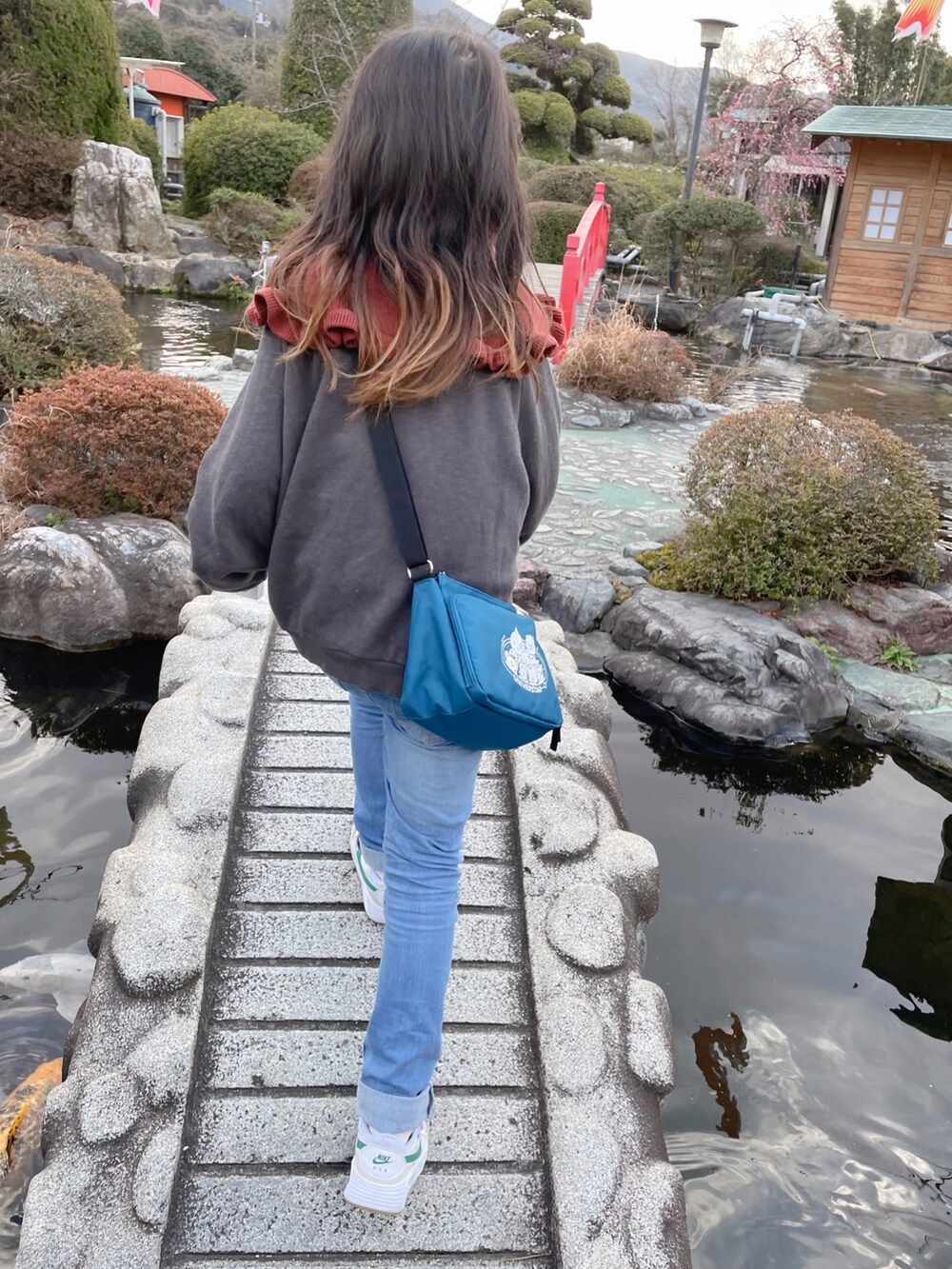 レッド系のニット/セーター、グレー系のスウェット、ブルー系のデニムパンツを着用したキッズの冬コーディネートの3枚目の写真