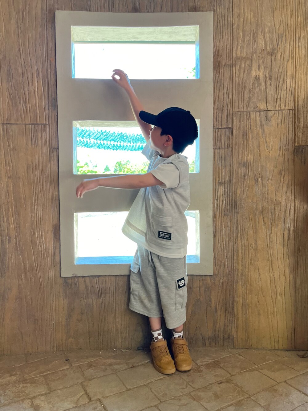 グレー系のトップス、グレー系のカーゴパンツ、ブラック系のキャップを着用したキッズの春コーディネートの5枚目の写真