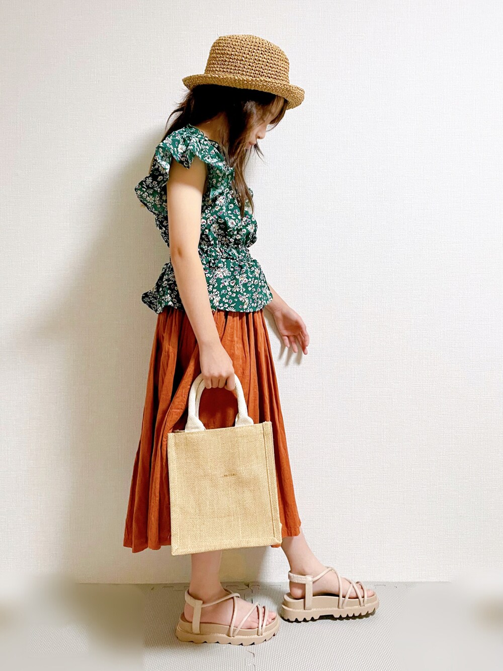 グリーン系のトップス、ブラウン系のスカート、ベージュ系のバッグを着用したキッズの夏コーディネートの3枚目の写真
