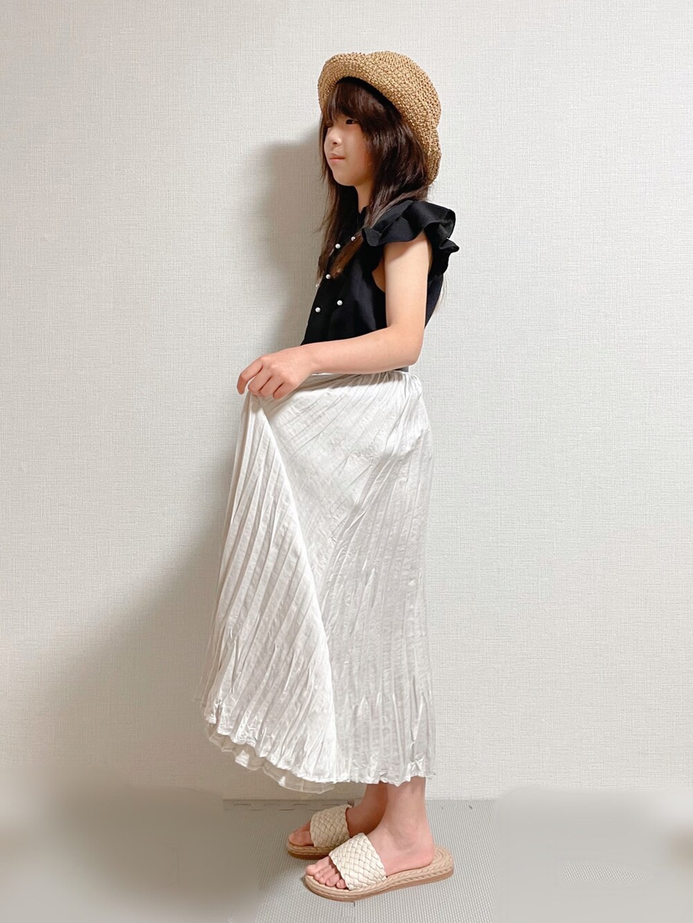 ブラック系のトップス、グレー系のスカート、ベージュ系のサンダルを着用したキッズの夏コーディネートの2枚目の写真