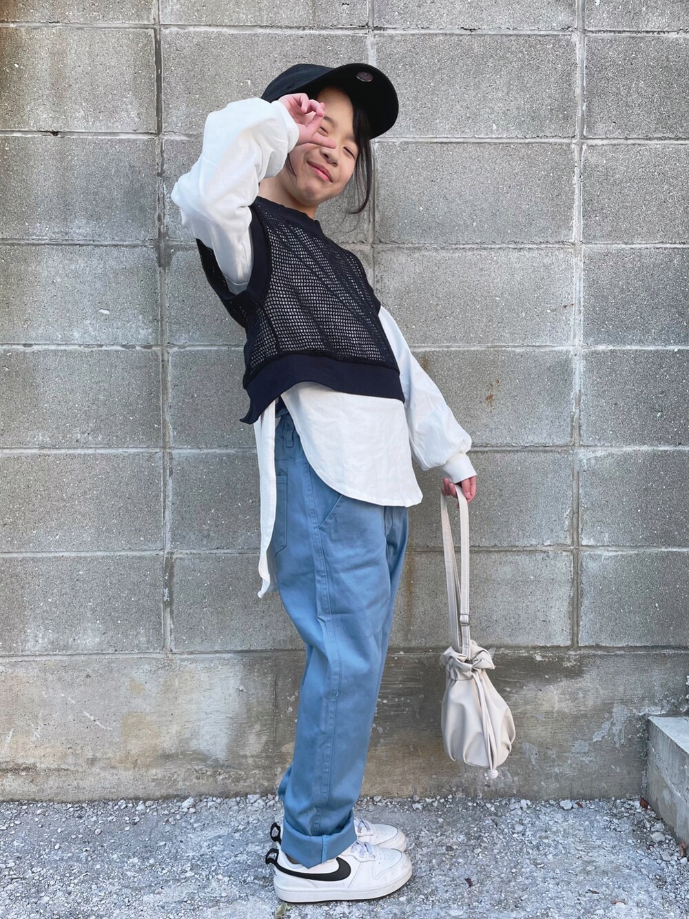 ブルー系のチノパンツ、ホワイト系のスニーカー、ホワイト系のショルダーバッグを着用したキッズの冬コーディネートの2枚目の写真
