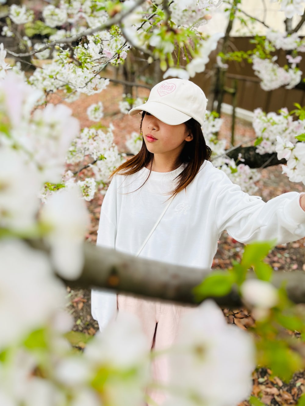 ホワイト系のトップス、ピンク系のデニムパンツ、ホワイト系のショルダーバッグを着用したキッズの春コーディネートの3枚目の写真