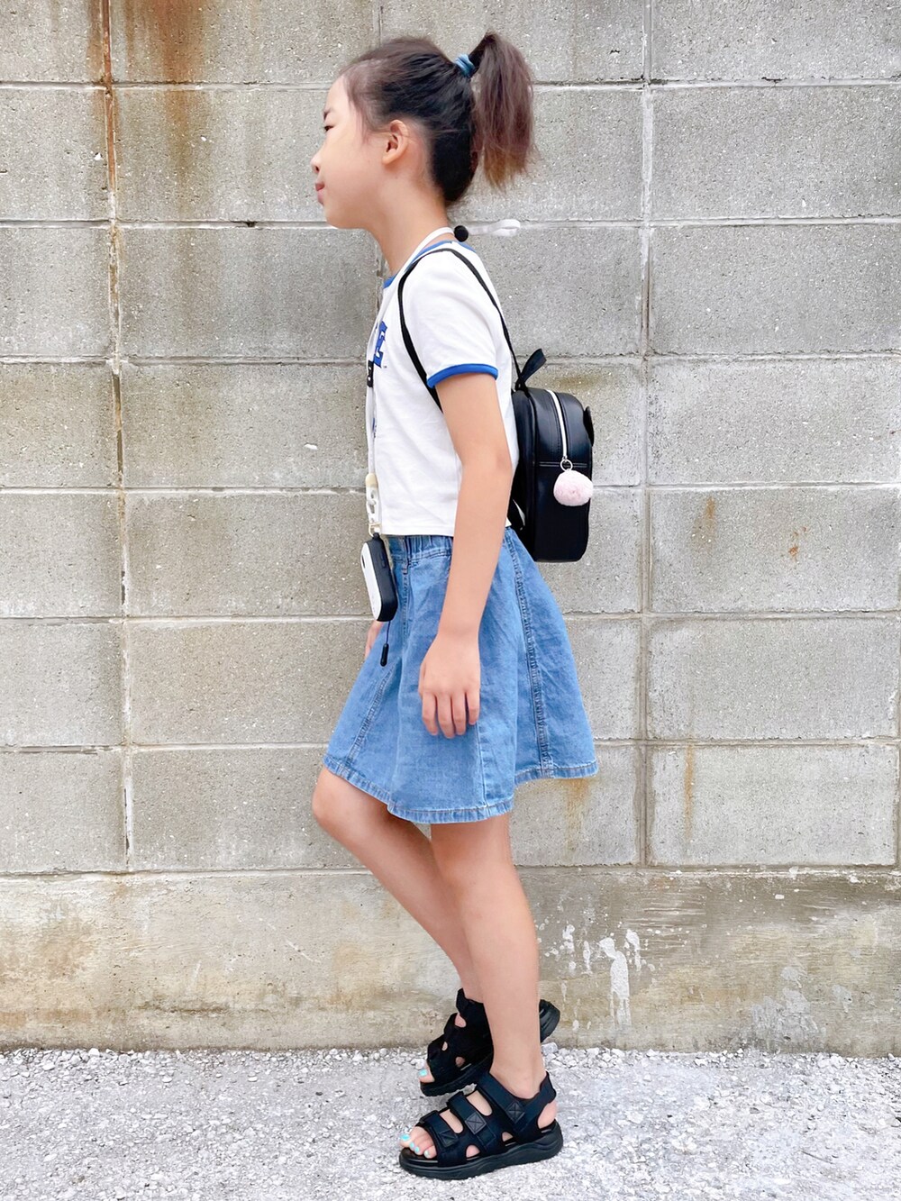 ブラック系のサンダル、ホワイト系のTシャツ/カットソー、ブルー系のデニムスカートを着用したキッズの夏コーディネートの3枚目の写真