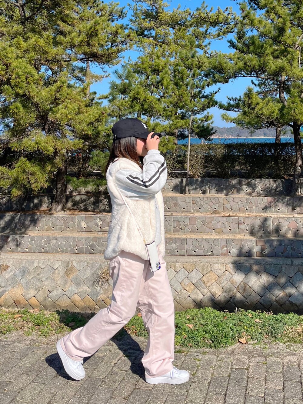 ピンク系のパンツ、ホワイト系のワンピース、ホワイト系のベストを着用したキッズの冬コーディネートの2枚目の写真
