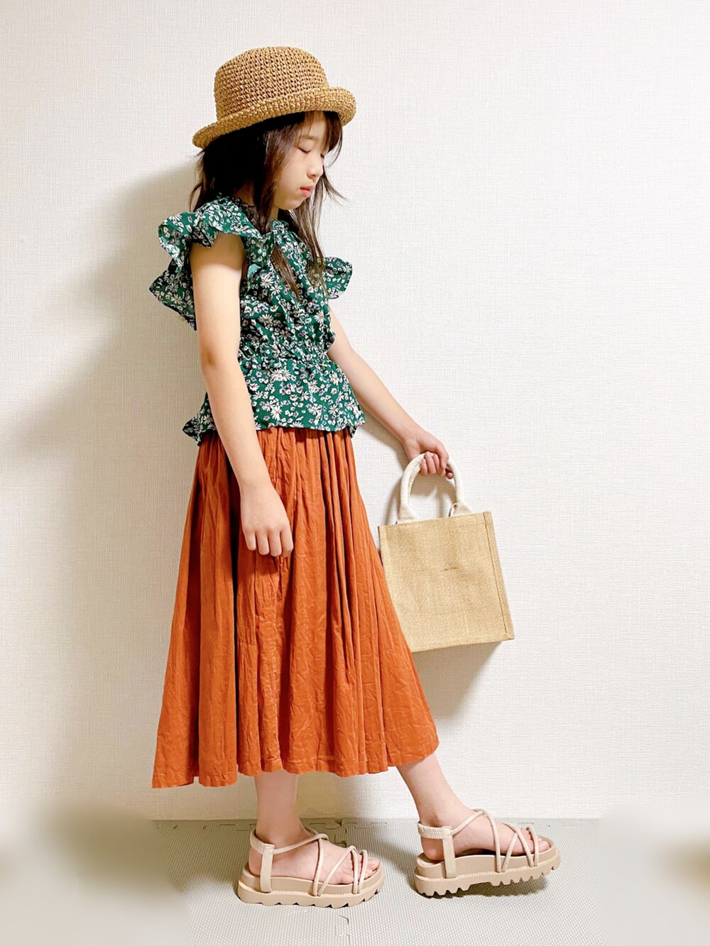 グリーン系のトップス、ブラウン系のスカート、ベージュ系のバッグを着用したキッズの夏コーディネートの2枚目の写真