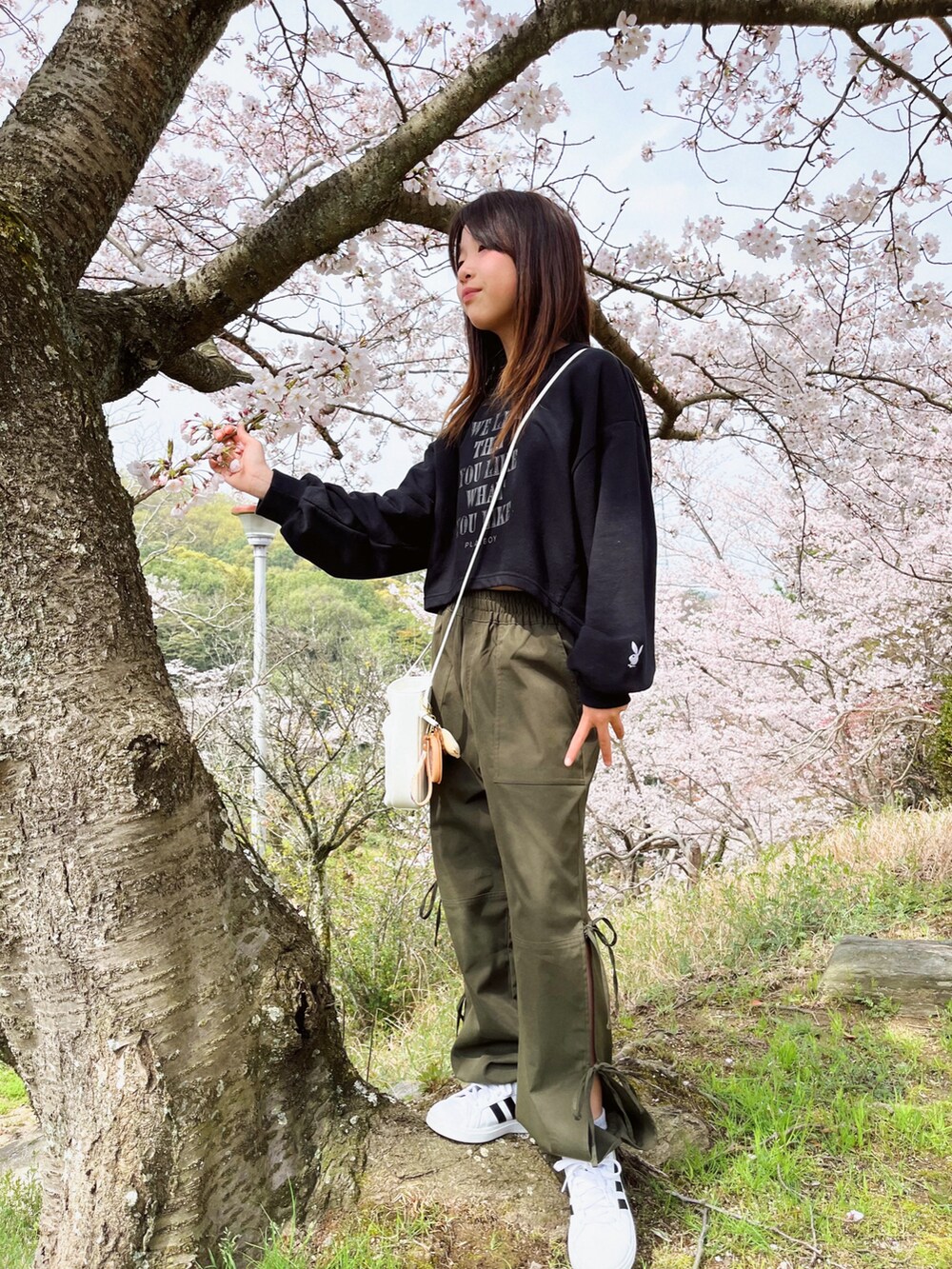 ブラック系のトップス、グリーン系のカーゴパンツ、ホワイト系のショルダーバッグを着用したキッズの春コーディネートの3枚目の写真