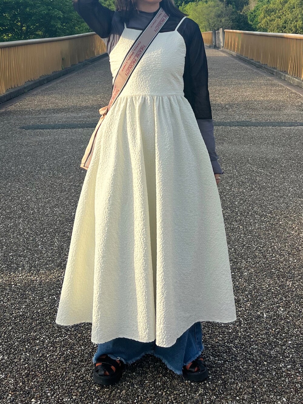 ホワイト系のワンピース/ドレス、ブルー系のデニムパンツ、ベージュ系のショルダーバッグを着用したレディースの春コーディネートの2枚目の写真