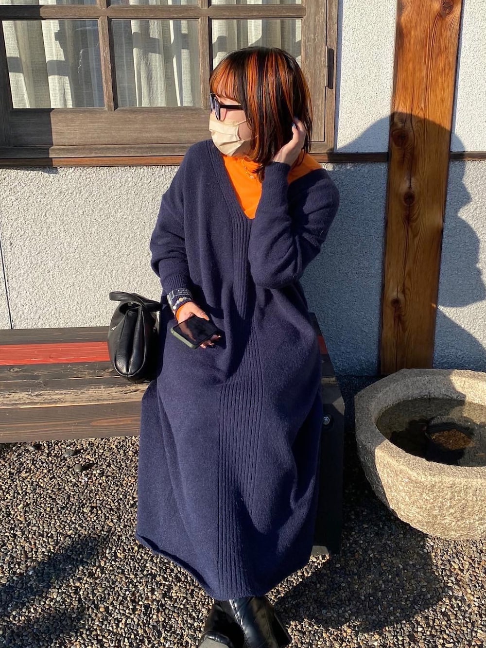 ブルー系のワンピース、オレンジ系のトップス、ブラック系のトートバッグを着用したレディースの冬コーディネートの2枚目の写真