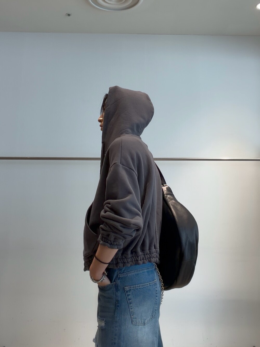 ブルー系のデニムパンツ、グレー系のパーカー、ブラック系のベルトを着用したメンズの夏コーディネートの5枚目の写真