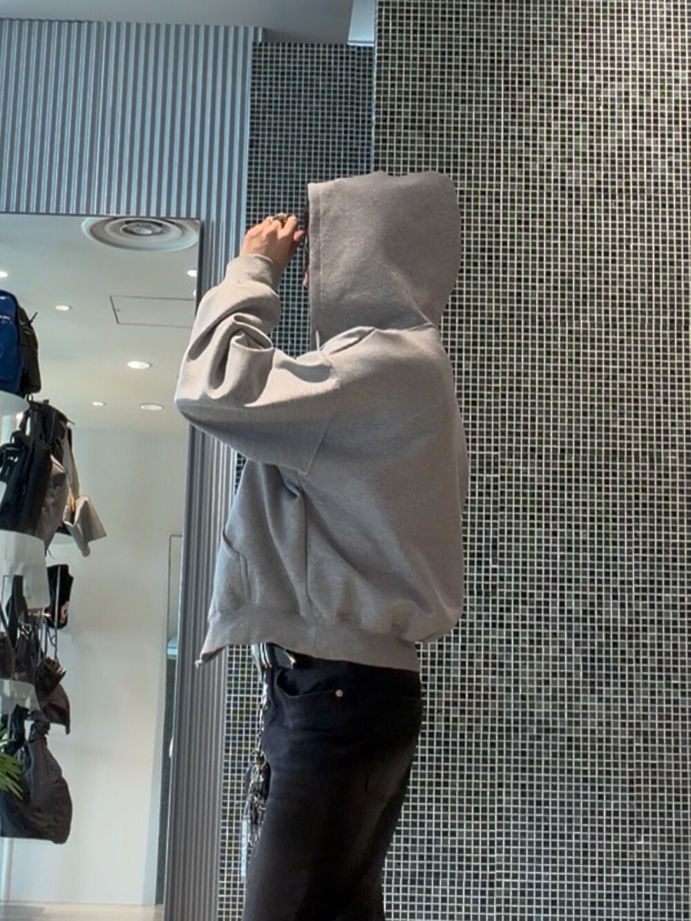 ブラック系のデニムパンツ、ホワイト系のタンクトップ、グレー系のパーカーを着用したメンズの夏コーディネートの6枚目の写真