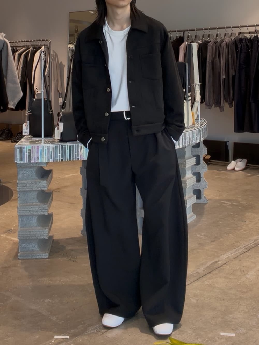 ブラック系のブルゾン、ブラック系のスラックス、ホワイト系のTシャツ/カットソーを着用したメンズの春コーディネートの2枚目の写真