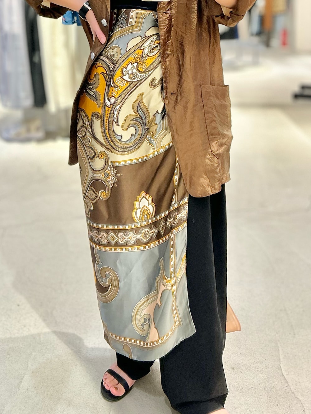 ブラウン系のテーラードジャケット、ブラック系のスラックス、ブラック系のサンダルを着用したレディースの春コーディネートの3枚目の写真