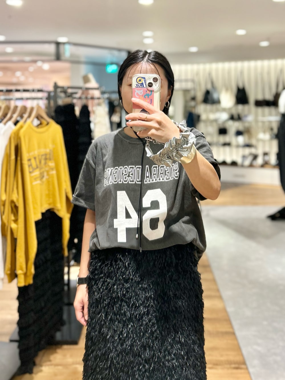 ブラック系のスカート、ブラック系のTシャツ/カットソー、ブラック系のスニーカーを着用したレディースの秋コーディネートの2枚目の写真