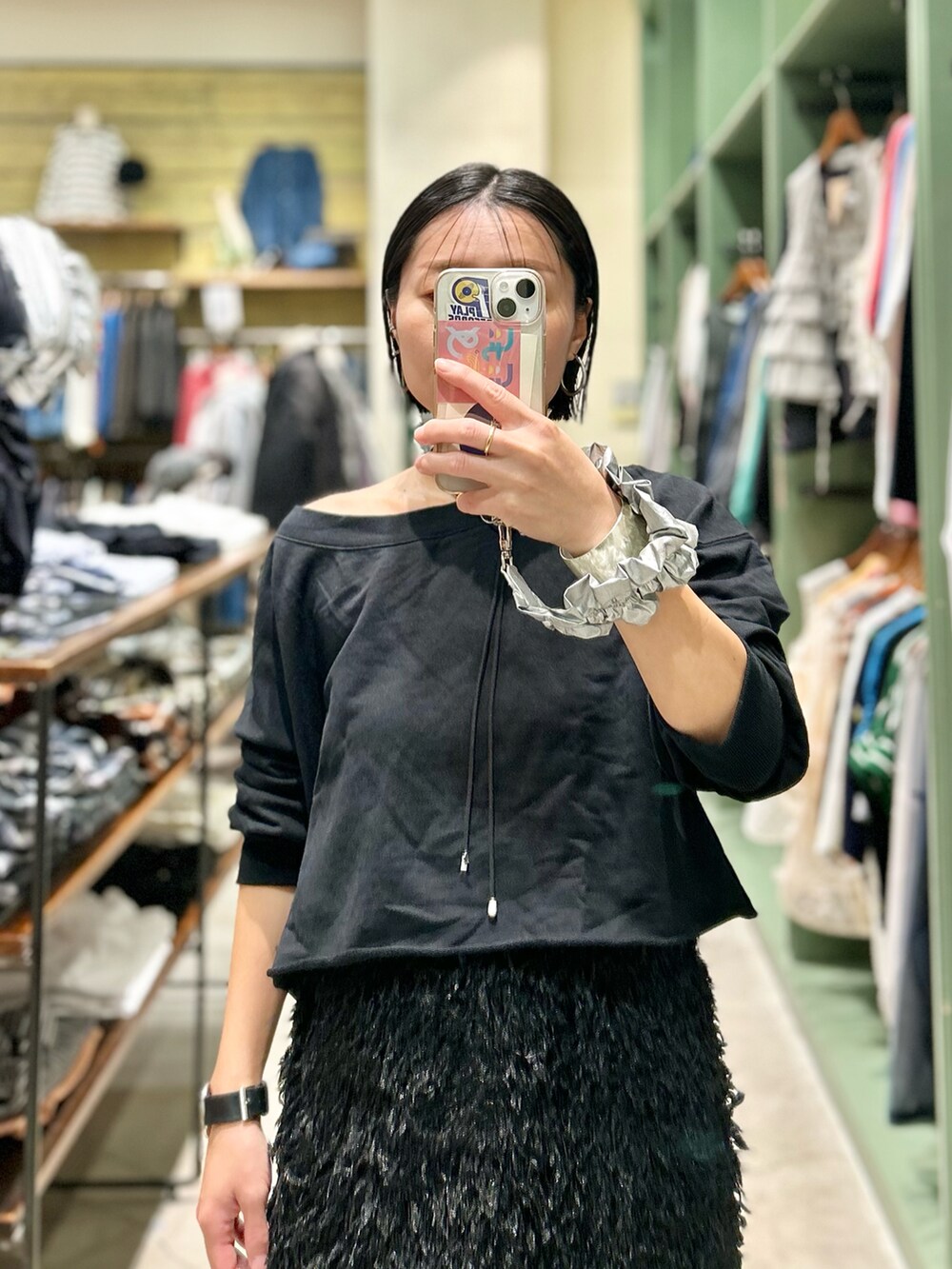 ブラック系のスウェット、ブラック系のスカート、ブルー系のデニムパンツを着用したレディースの秋コーディネートの2枚目の写真