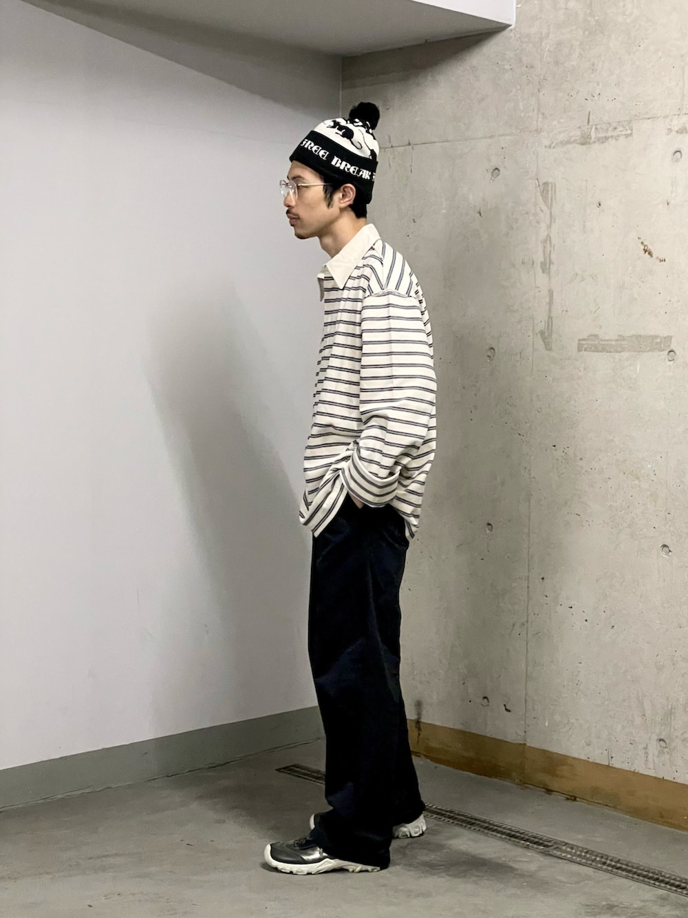 ブラック系のスラックス、ホワイト系のポロシャツ、シルバー系のスニーカーを着用したメンズの秋コーディネートの2枚目の写真