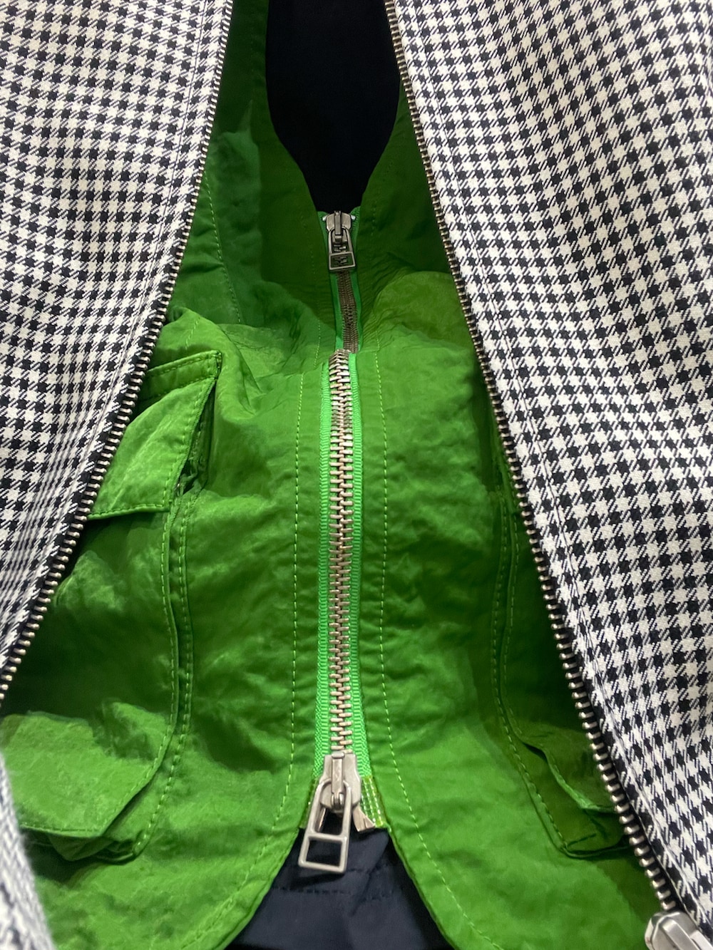 ホワイト系のブルゾン、グリーン系のベスト、ブラック系のスラックスを着用したメンズの春コーディネートの3枚目の写真