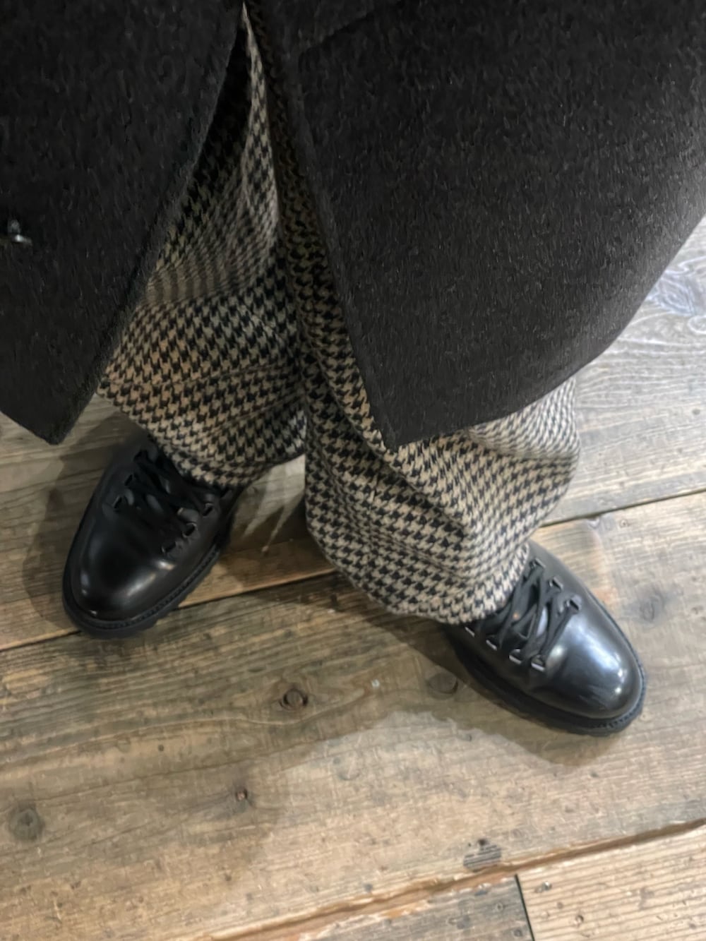 グレー系のトレンチコート、ブラック系のブーツ、ベージュ系のスラックスを着用したメンズの冬コーディネートの2枚目の写真