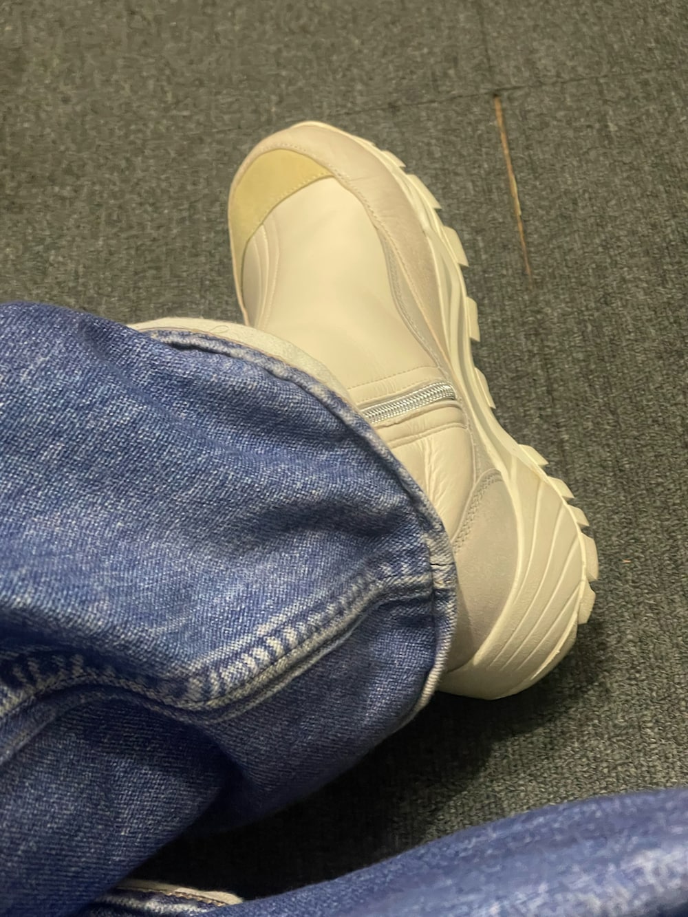 レッド系のニット/セーター、ホワイト系のブーツ、ブルー系のデニムパンツを着用したメンズの冬コーディネートの3枚目の写真