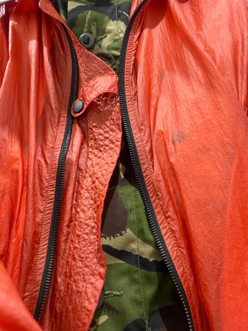 オレンジ系のナイロンジャケット、ブラック系のデニムパンツ、ホワイト系のスニーカーを着用したメンズの春コーディネートの2枚目の写真