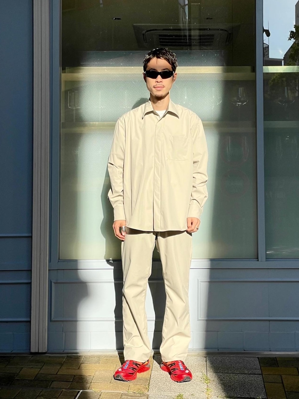 レッド系のスニーカー、ベージュ系のシャツ/ブラウス、ベージュ系のデニムパンツを着用したメンズの秋コーディネートの2枚目の写真