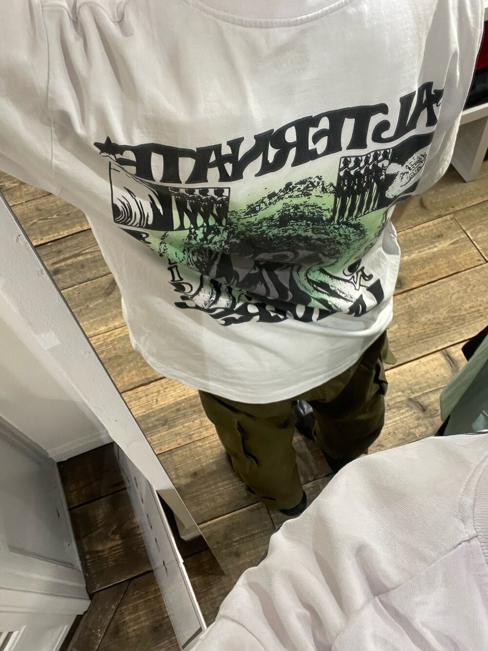 ホワイト系のTシャツ/カットソー、グリーン系のカーゴパンツ、ブラック系のブーツを着用したメンズの夏コーディネートの2枚目の写真