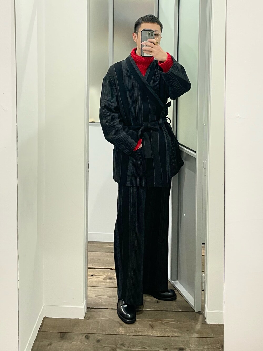 レッド系のニット/セーター、ブラック系のブーツを着用したメンズの冬コーディネートの2枚目の写真