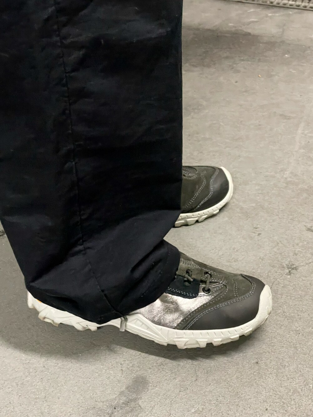 ブラック系のスラックス、ホワイト系のポロシャツ、シルバー系のスニーカーを着用したメンズの秋コーディネートの5枚目の写真