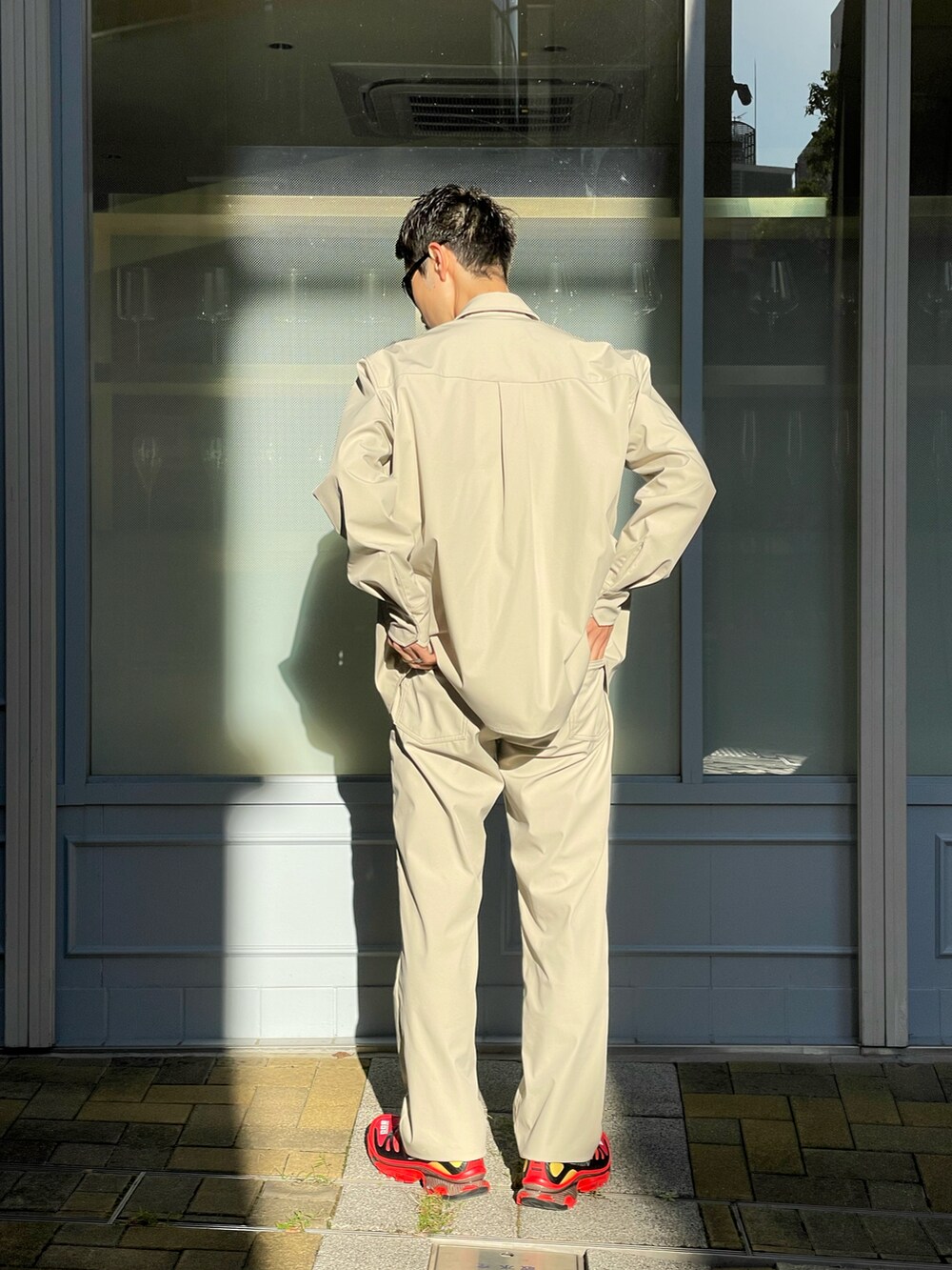 レッド系のスニーカー、ベージュ系のシャツ/ブラウス、ベージュ系のデニムパンツを着用したメンズの秋コーディネートの3枚目の写真