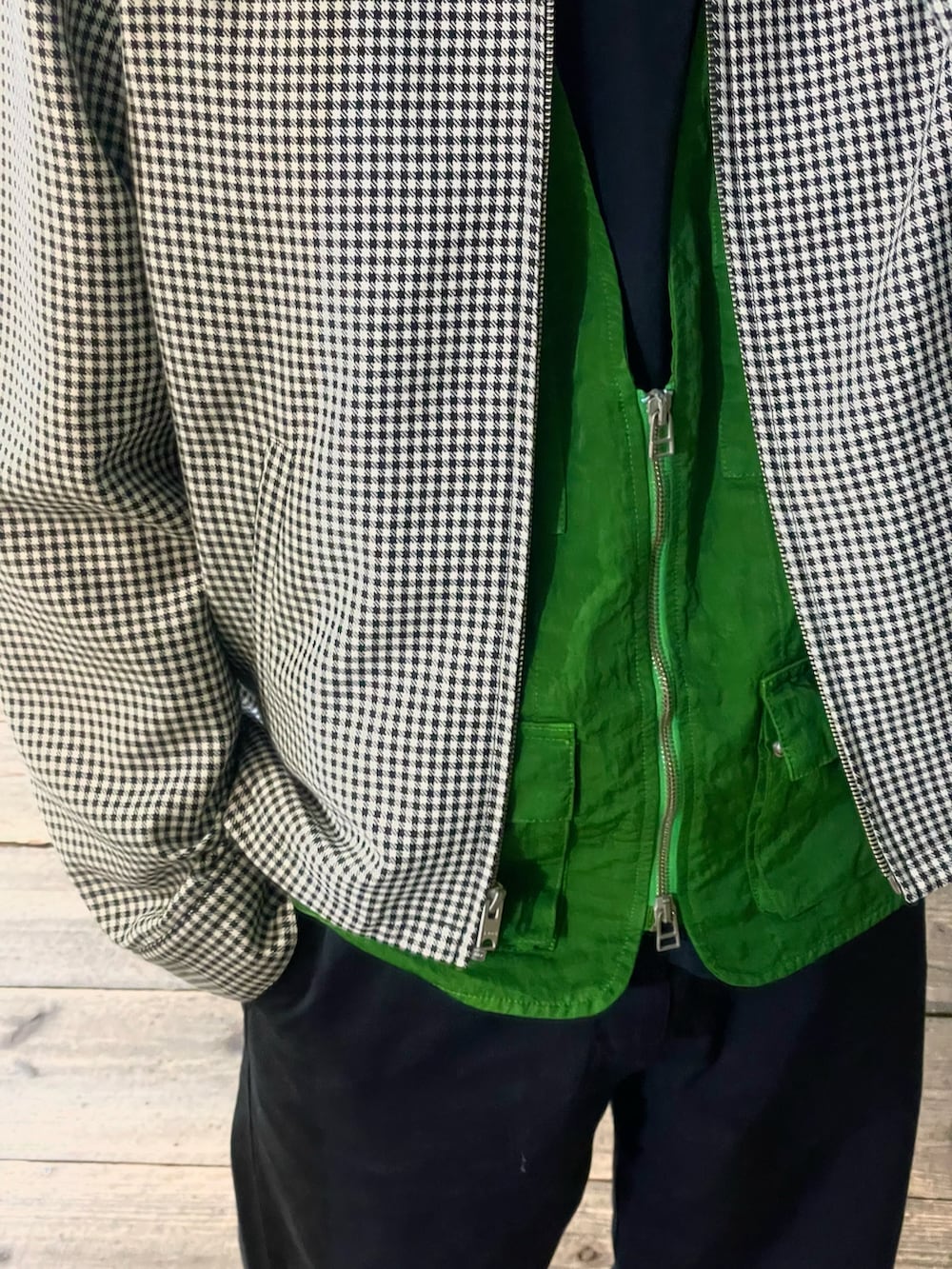 ホワイト系のブルゾン、グリーン系のベスト、ブラック系のスラックスを着用したメンズの春コーディネートの2枚目の写真